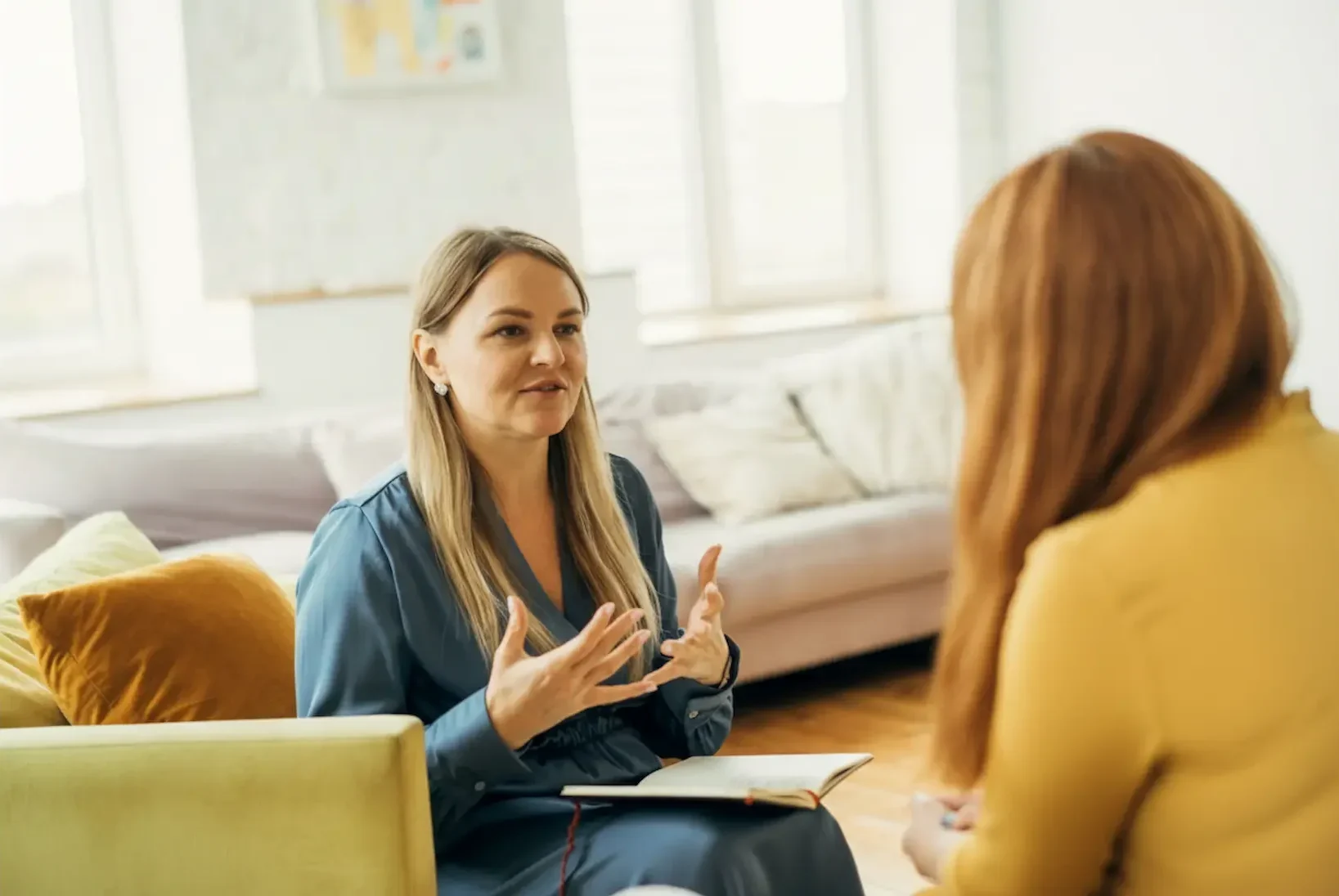 A blonde psychiatrist uses expressive hand gestures while talking to a patient, showcasing the active communication style of the right psychiatrist.