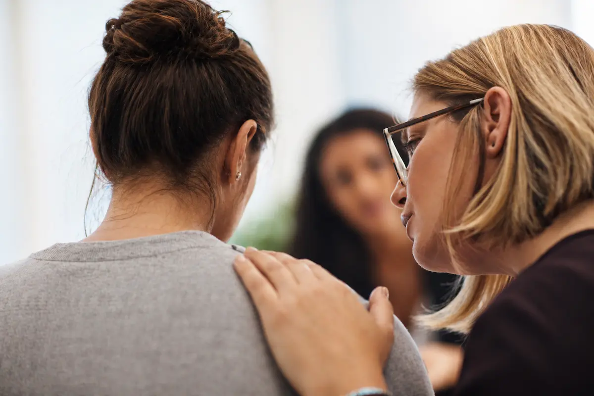 Therapist offering support to a distressed woman during a counseling session for grief disorder recovery.