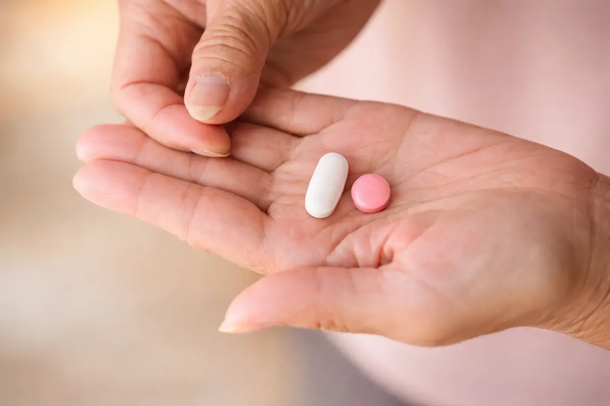 Close-up of a hand holding two tablets, demonstrating medication management and correct dosage use.