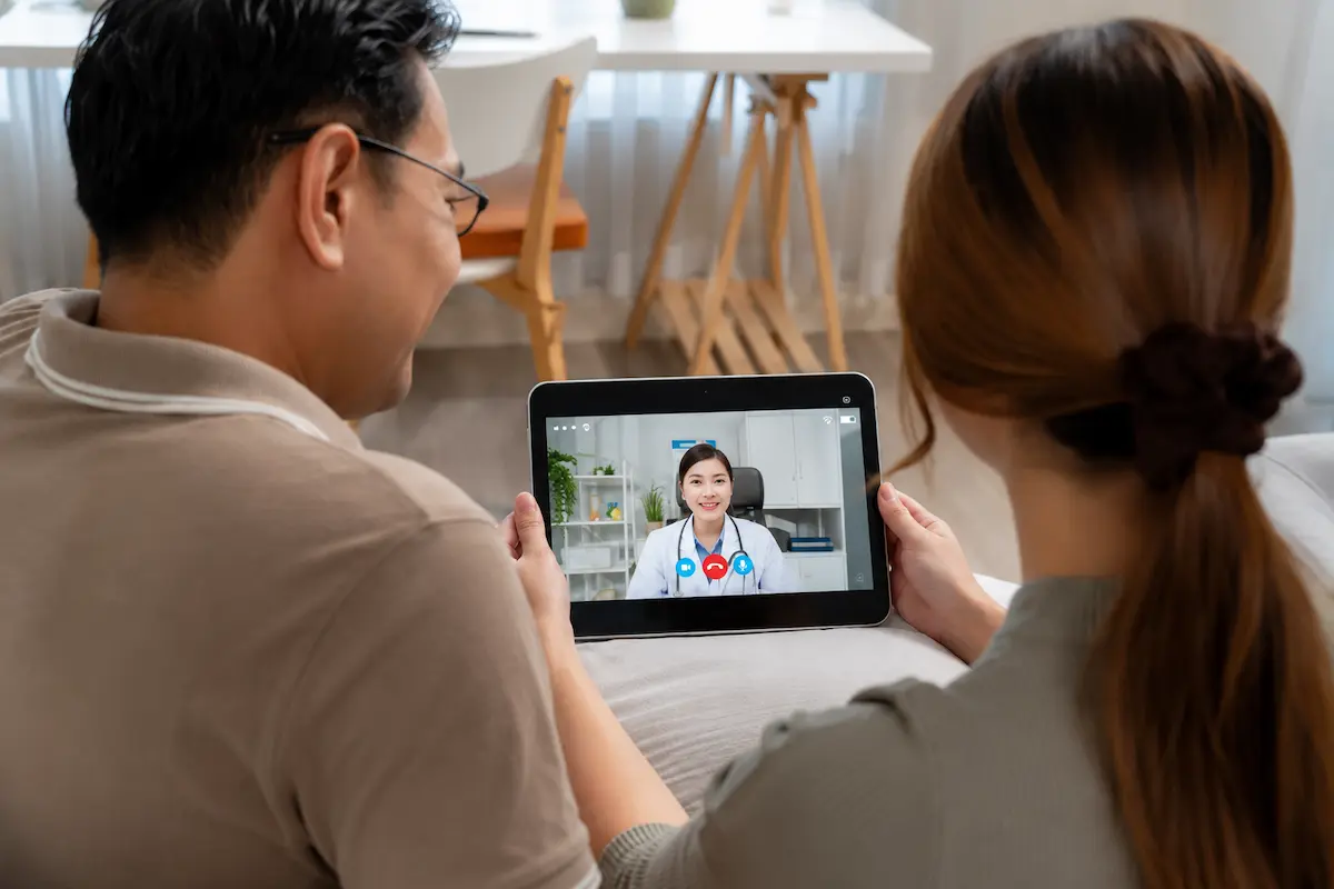 Couple attending a telepsychiatry for insomnia video consultation with an online doctor using a tablet at home.