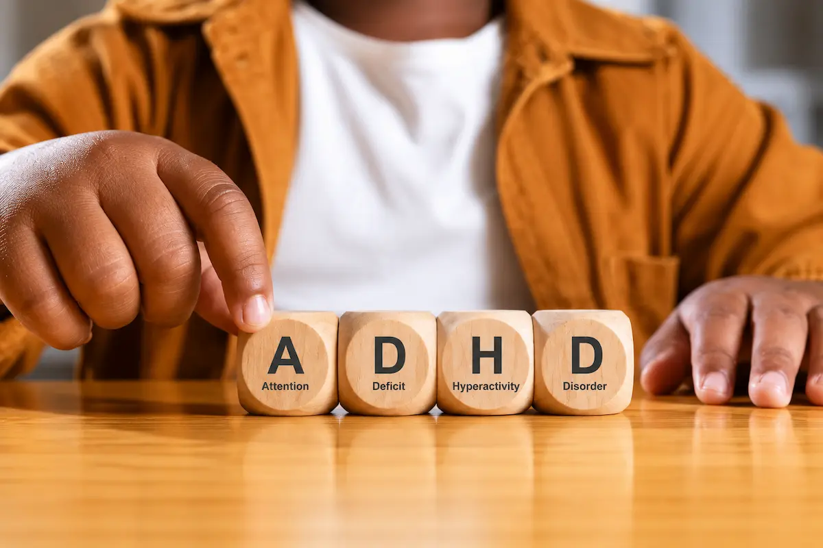 Close-up of a woman touching wooden ADHD blocks, symbolizing ADHD in adult women and challenges with focus, organization, and executive function.