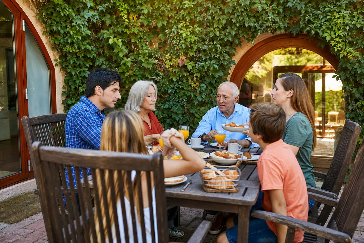 Multigenerational Hispanic family sharing a meal, representing culturally responsive care from a Spanish speaking psychiatrist.